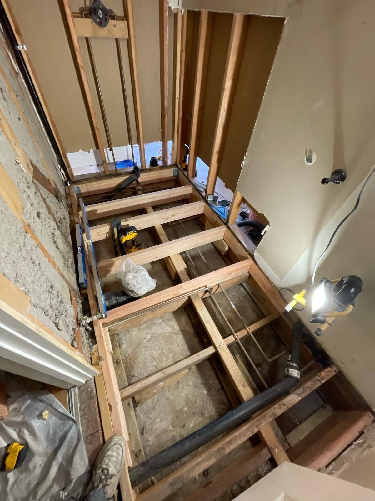 A bathroom under construction with wooden beams and pipes.