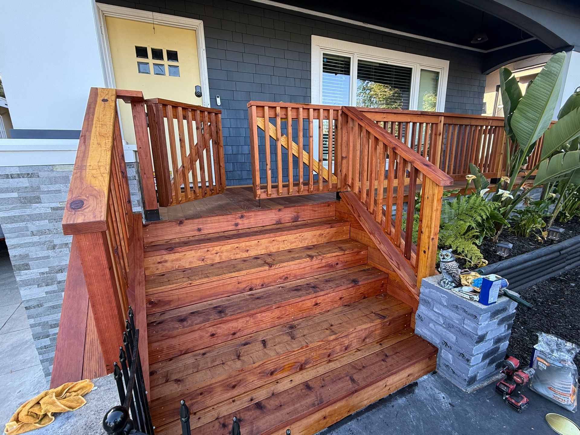 A wooden deck with stairs and a railing in front of a house.