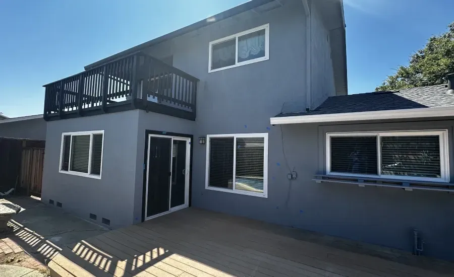 The back of a house with a deck and a balcony.