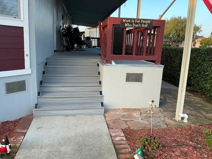 Composite deck remodel featuring gray low-maintenance decking boards, upgraded stair system with integrated step lighting, refreshed porch surface, and improved outdoor living functionality. Exterior renovation completed by Dream Build Services, specializing in deck replacement, composite decking installation, porch remodeling, and residential exterior upgrades in the Bay Area.