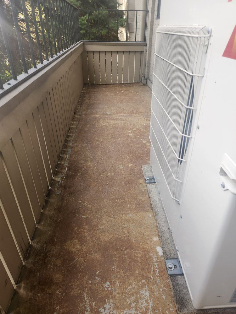 A large white air conditioner is sitting on the side of a balcony.