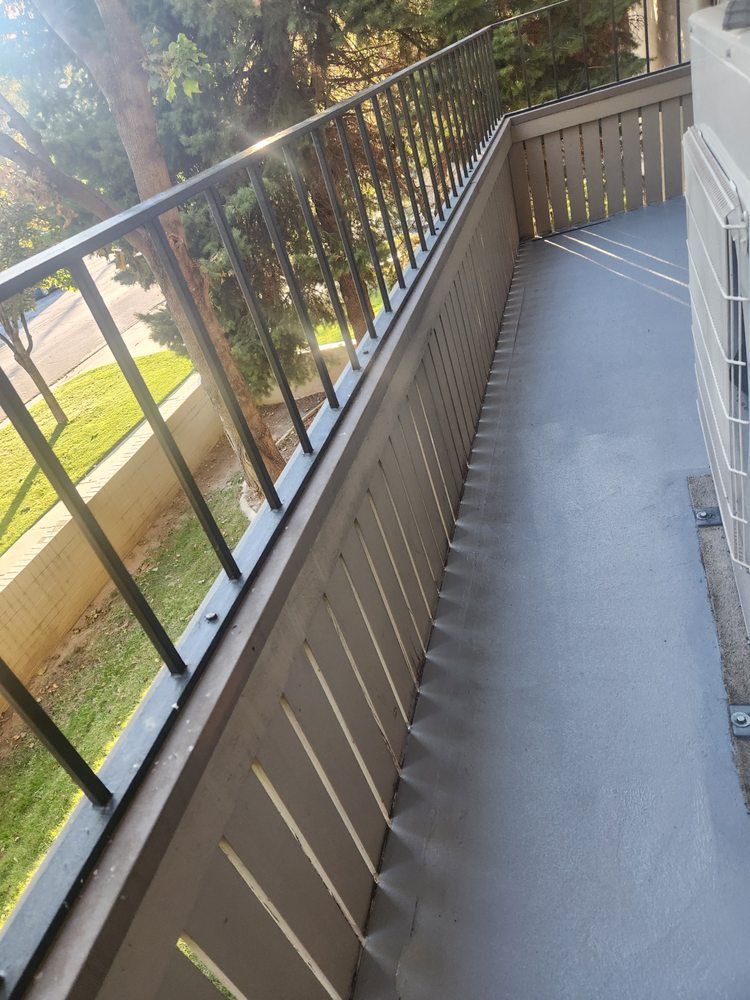 A balcony with a metal railing and a concrete floor.