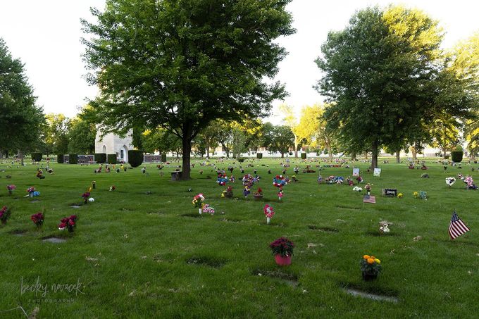 a couple with flowers in front of a gravestone