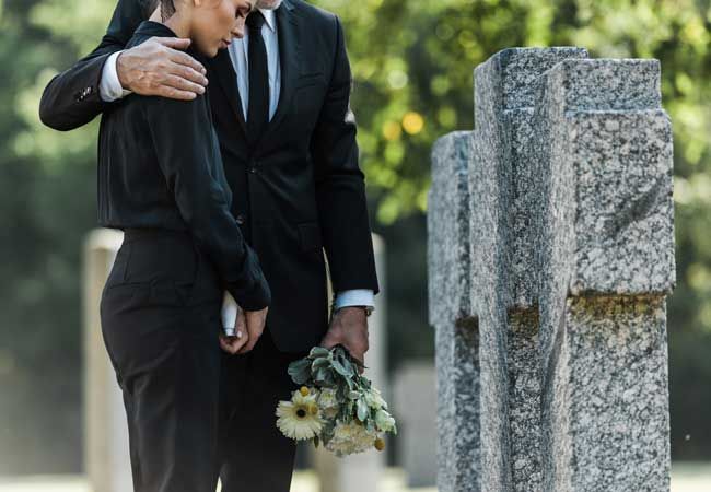 a couple with flowers in front of a gravestone