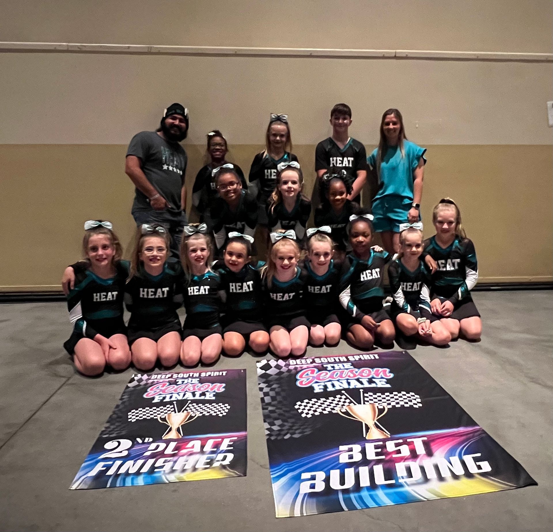 A group of cheerleaders are posing for a picture in front of two posters that say best building
