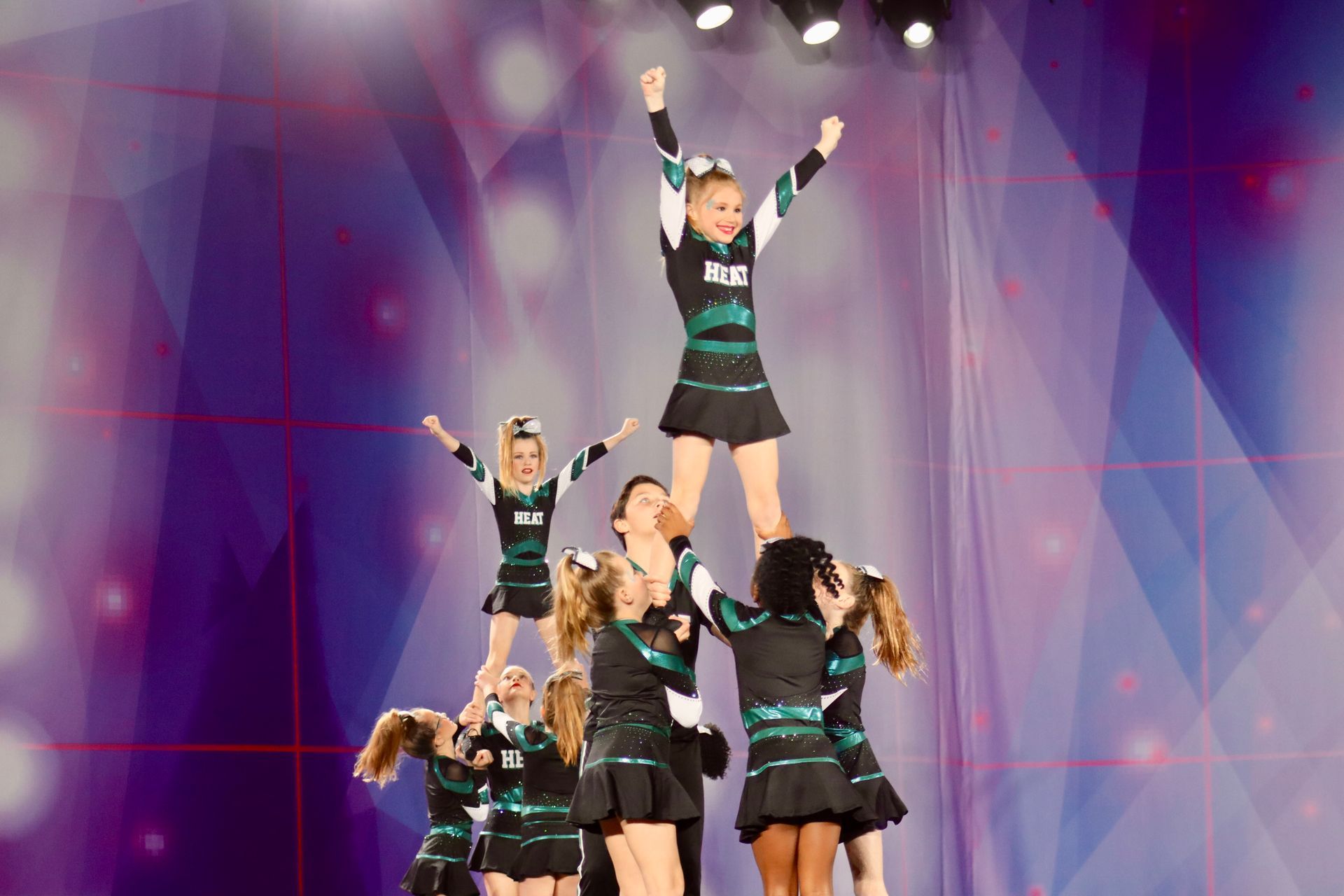 A group of cheerleaders are performing a stunt on a stage.