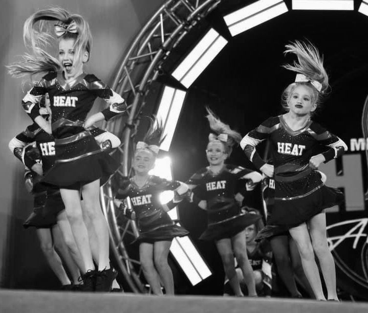 A black and white photo of cheerleaders wearing heat uniforms