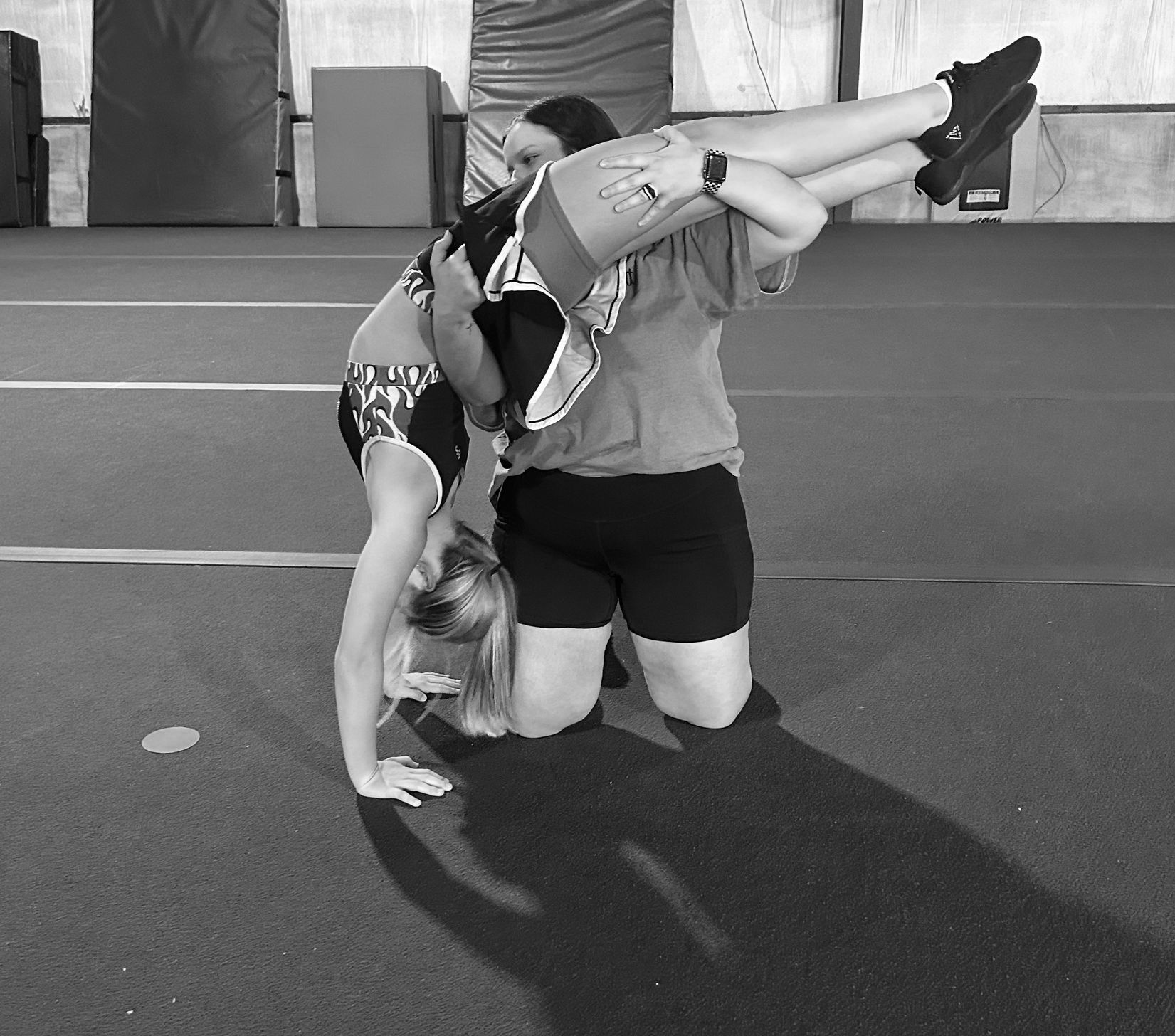 A black and white photo of two women kneeling on a gym floor