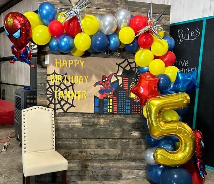 A spiderman birthday party with balloons and a chair