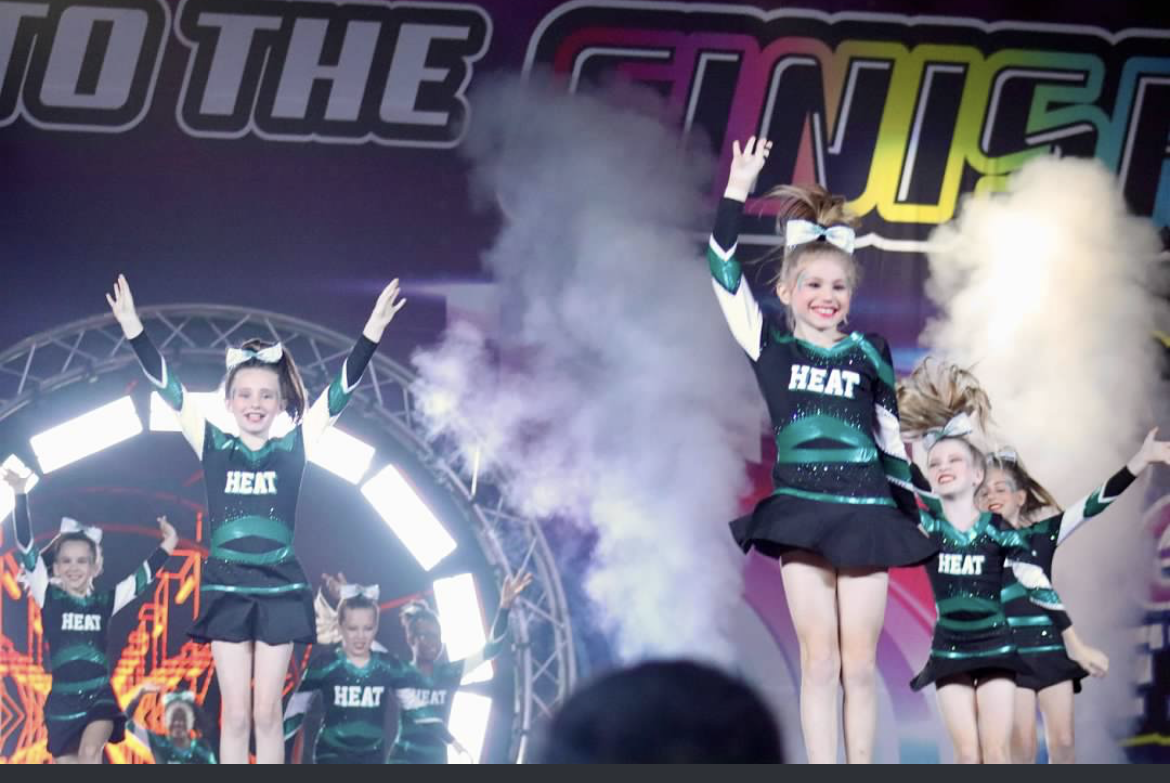 A group of cheerleaders are performing in front of a sign that says to the finish