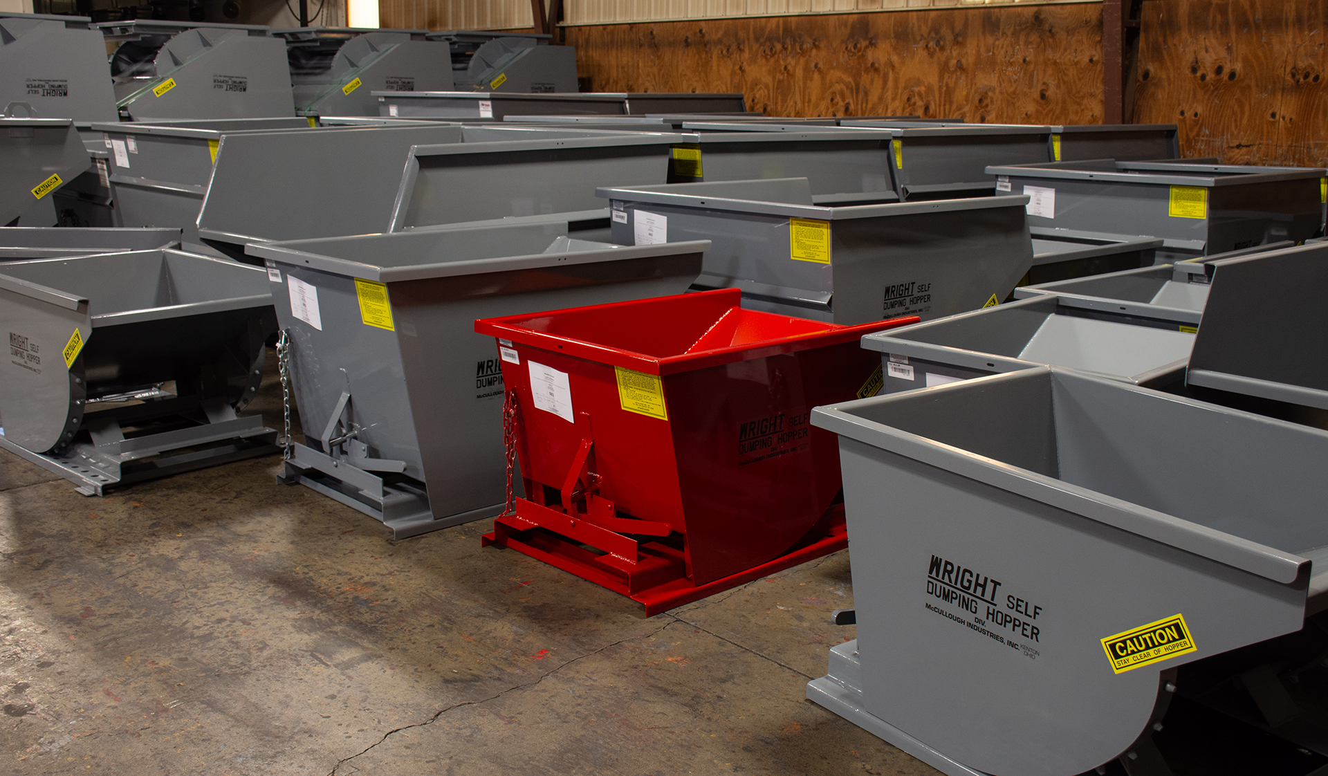 Two large, angled metal bins: one red and one orange, on a textured background.