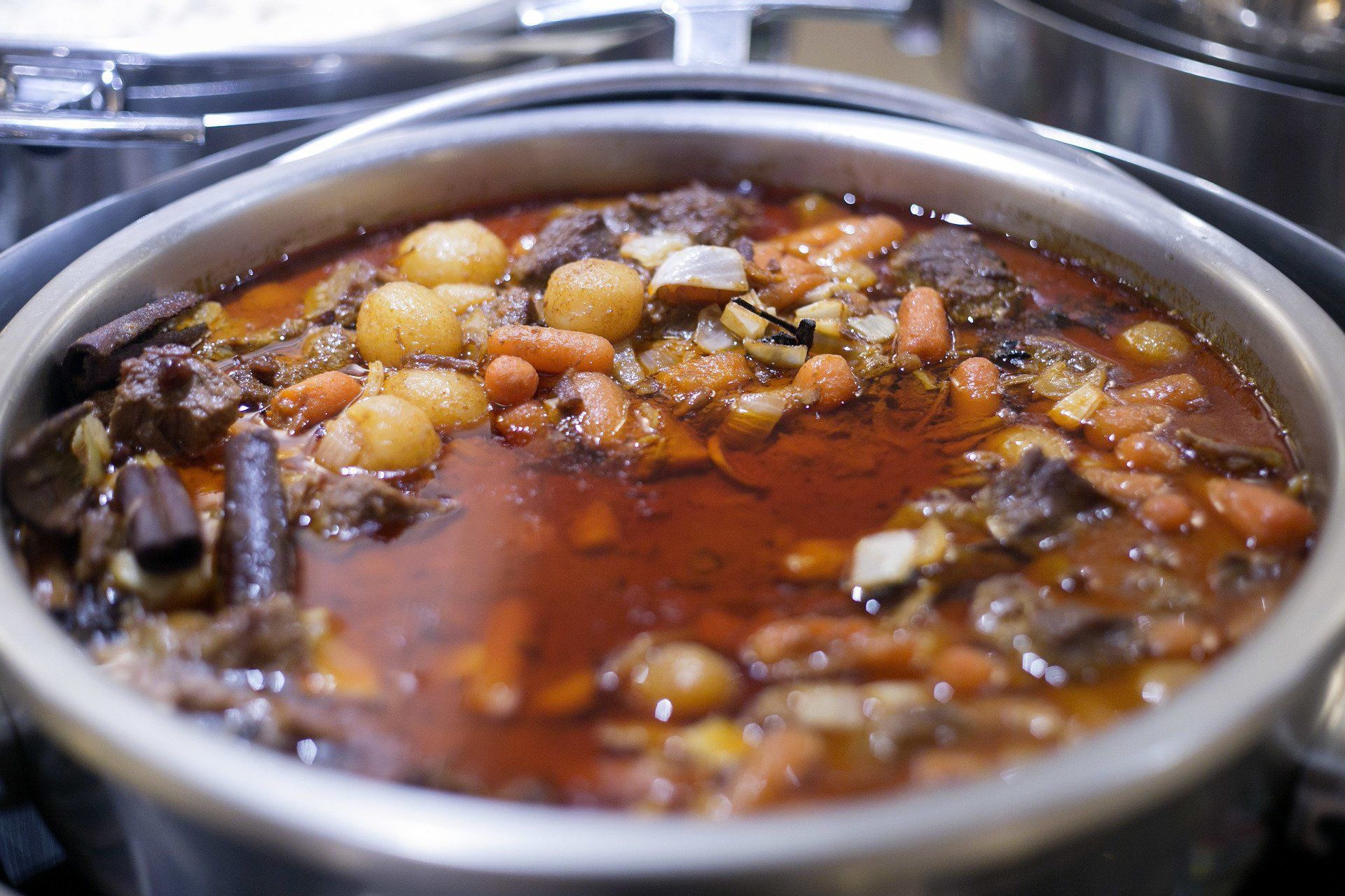 Ensopado com carne, cenoura e vegetais redondos em uma panela de metal.