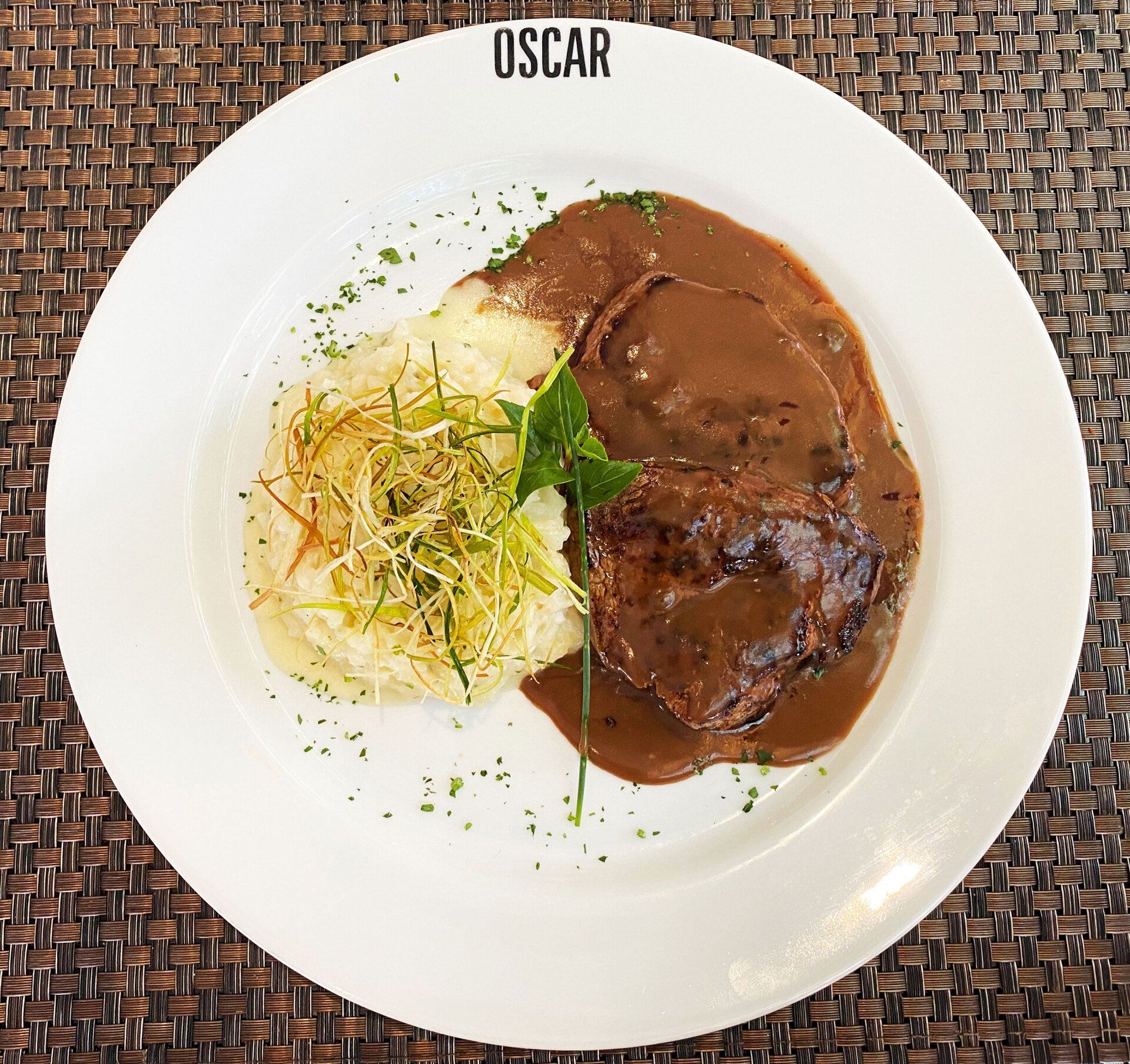 Prato de comida no restaurante Oscar, com bife, purê de batatas e molho.