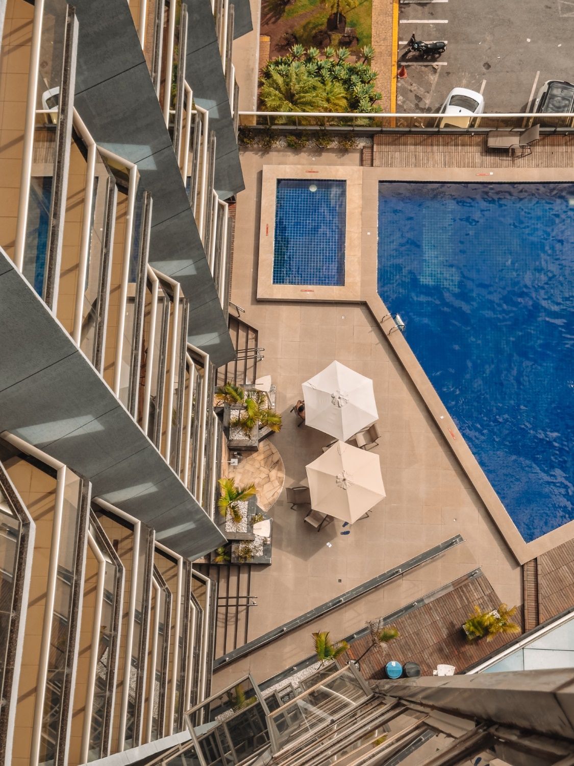 Vista de cima de um edifício com piscina e pátio com guarda-sóis.
