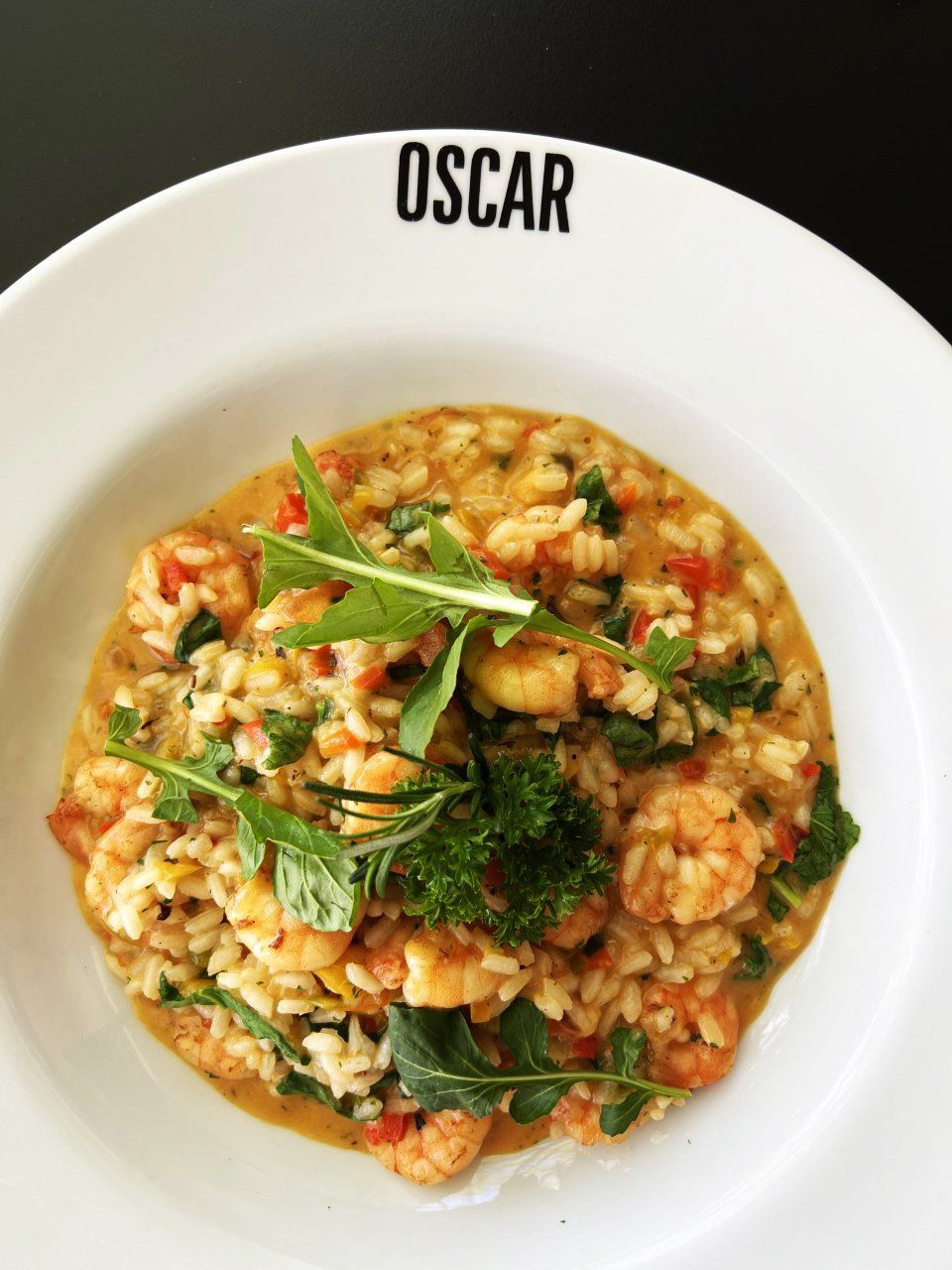 Risoto de camarão com rúcula e salsa, servido em tigela branca, com a marca 