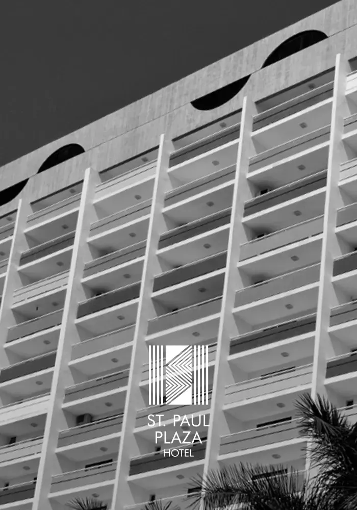 St. Paul Plaza Hotel, um edifício alto de concreto com varandas, logotipo e palmeira.