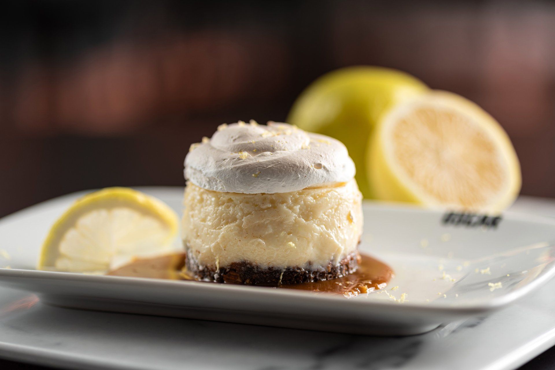Cheesecake de limão com cobertura de merengue em um prato branco, decorado com fatias de limão.