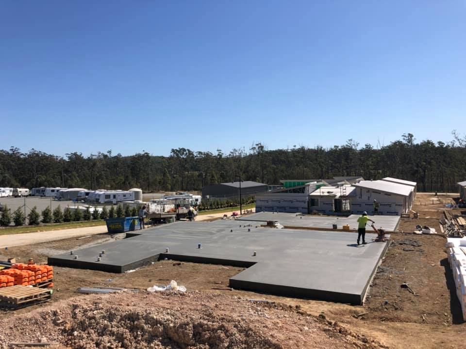 A Man Is Standing On A Concrete Floor In A Construction Site — Luke Seears Concreting in Port Macquarie, NSW