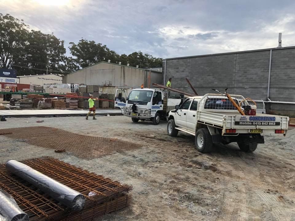Two Trucks Are Parked In A Dirt Lot In Front Of A Building — Luke Seears Concreting in Port Macquarie, NSW