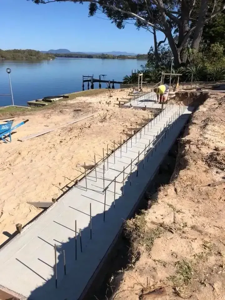 A Concrete Walkway Is Being Built Next To A Body Of Water — Luke Seears Concreting in Port Macquarie, NSW