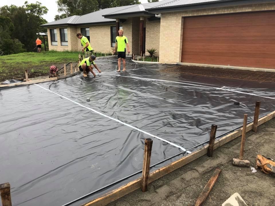 A Group Of People Are Working On A Driveway In Front Of A House — Luke Seears Concreting in Lake Cathie, NSW