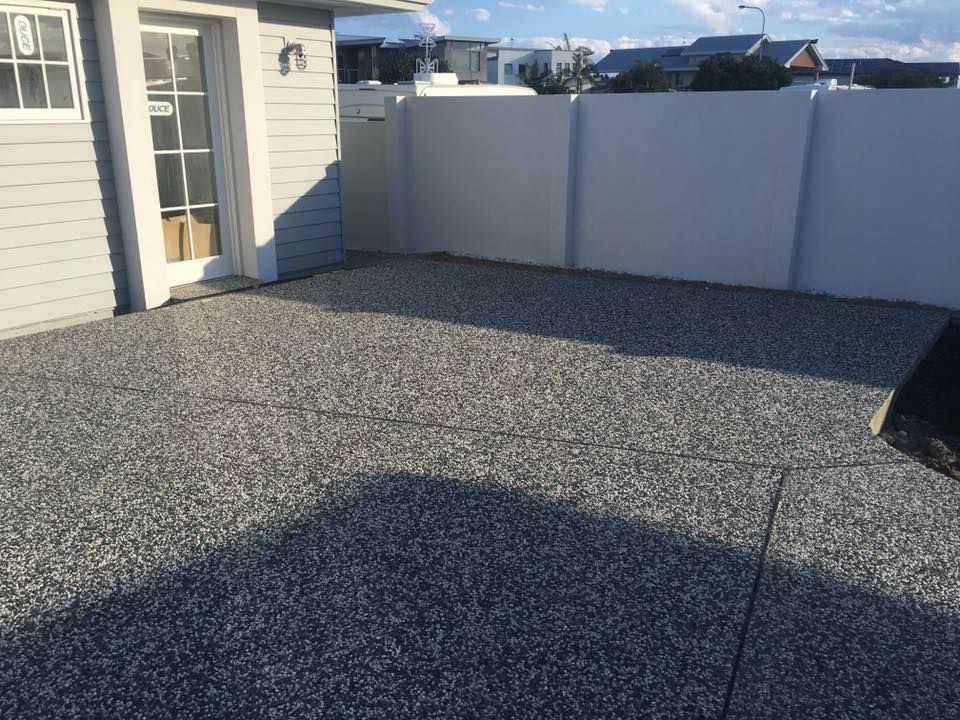 A White Fence Surrounds A Concrete Driveway In Front Of A House — Luke Seears Concreting in Lake Cathie, NSW