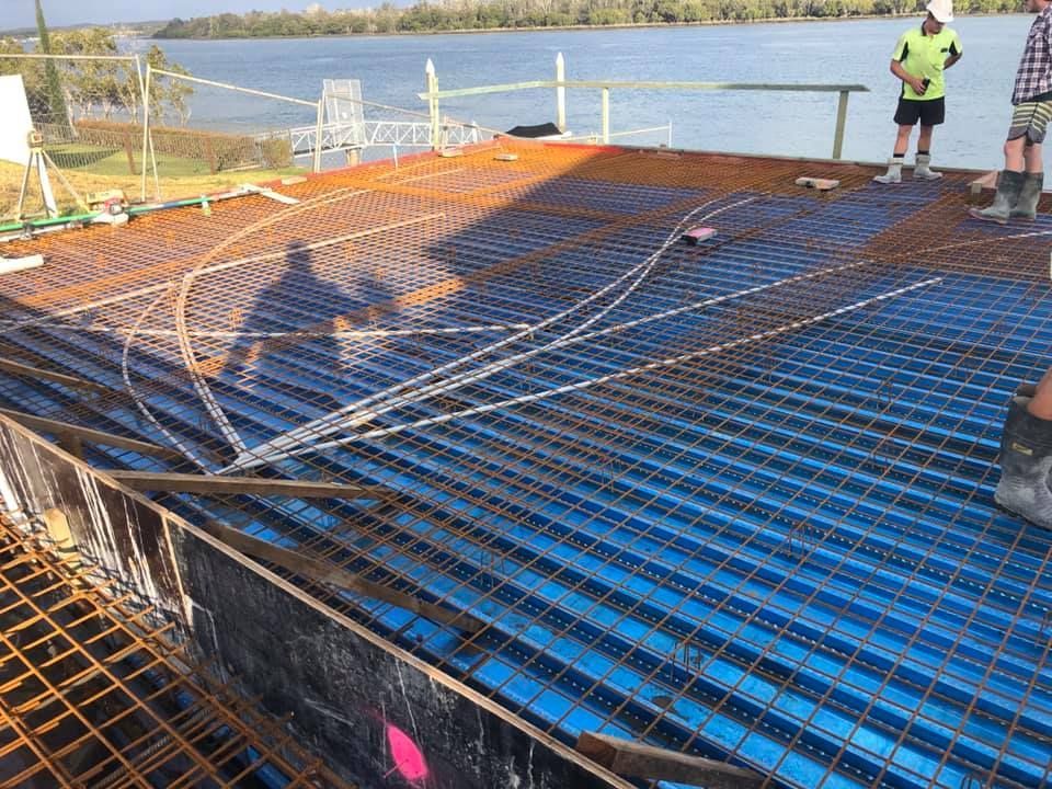 A Group Of Construction Workers Are Working On A Bridge Over A Body Of Water — Luke Seears Concreting in Port Macquarie, NSW