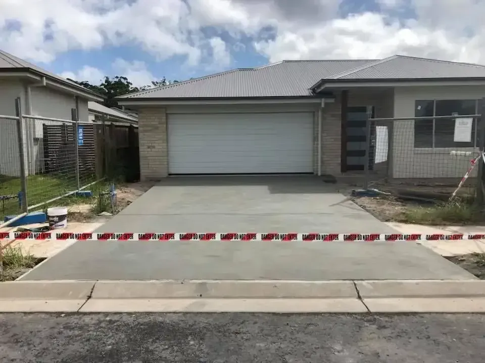 A Concrete Driveway In Front Of A House With A White Garage Door — Luke Seears Concreting in Port Macquarie, NSW
