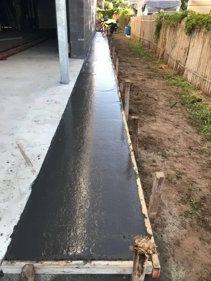 A Concrete Walkway Is Being Built Next To A Fence — Luke Seears Concreting in Port Macquarie, NSW