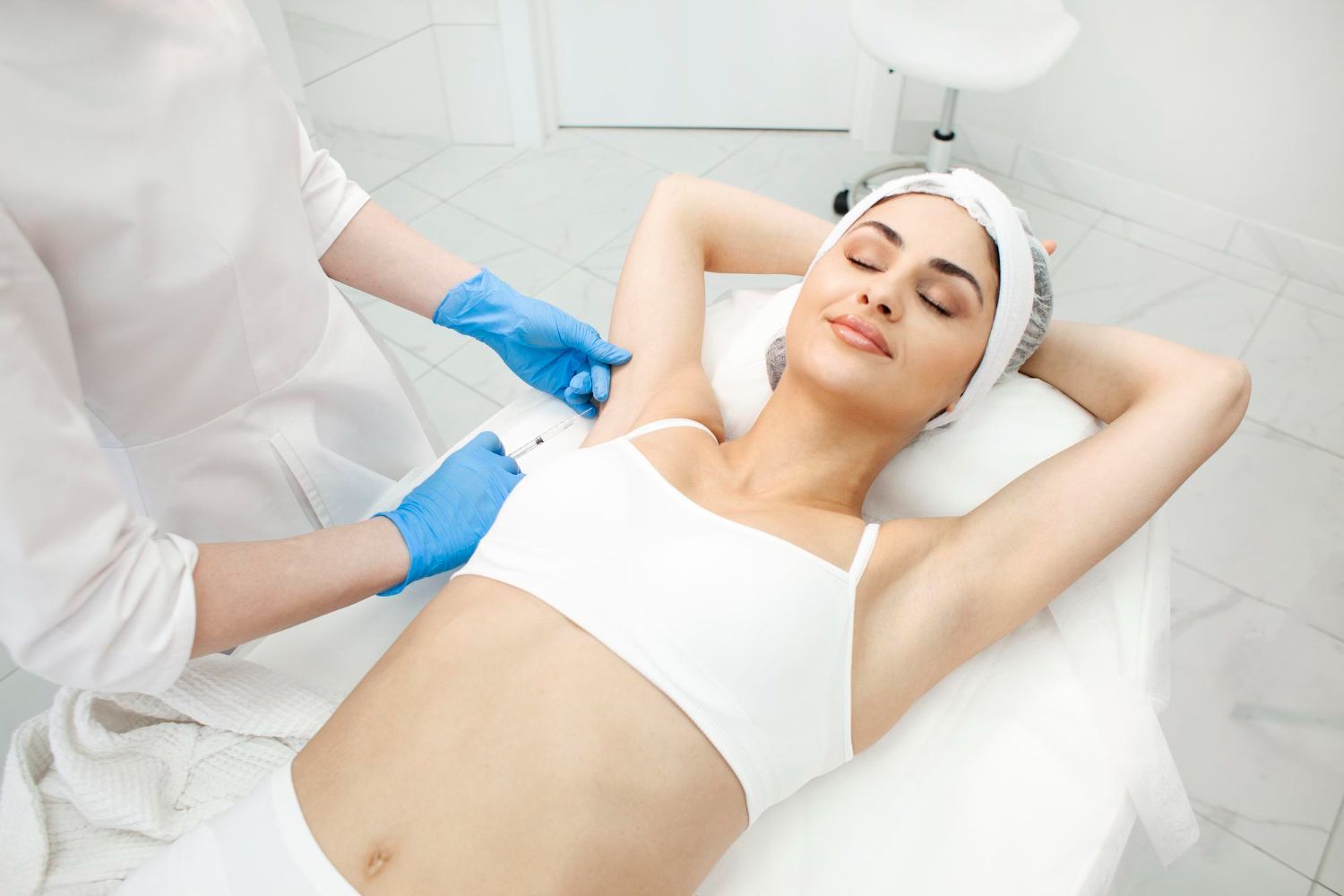 Technician adjusting a woman's treatment bandage in a bright spa clinic room