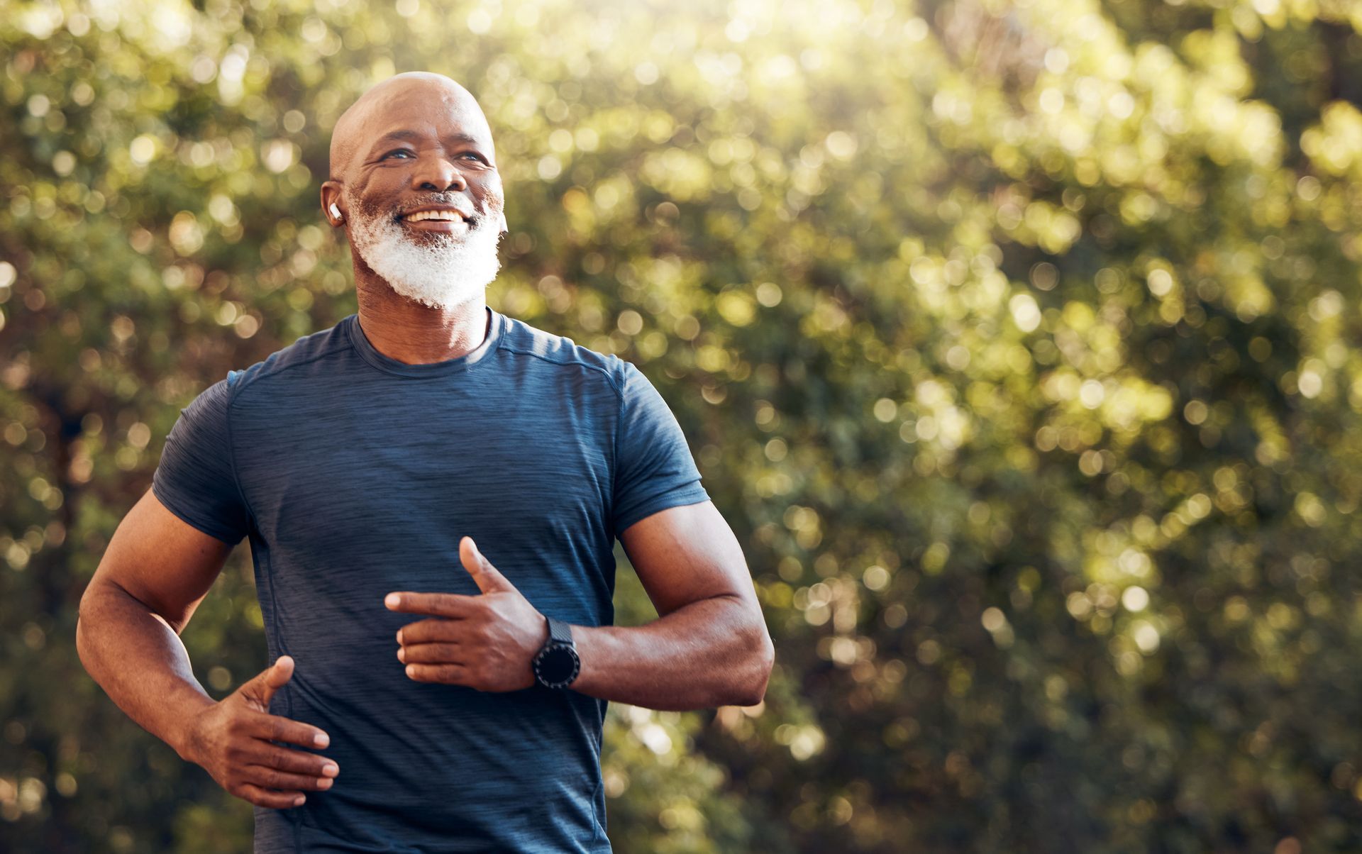 A man with a beard is running in a park.