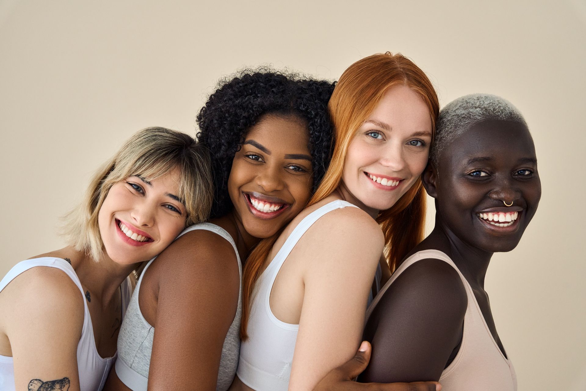 Four women of different races are posing for a picture together and smiling.