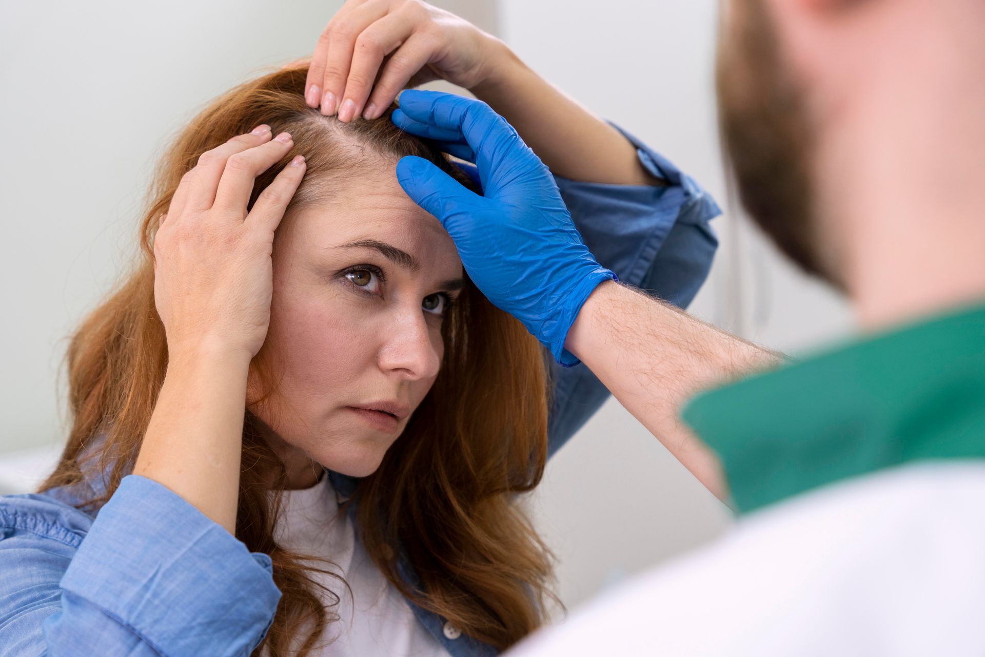 Woman with thinning red hair, examined by a doctor wearing gloves.