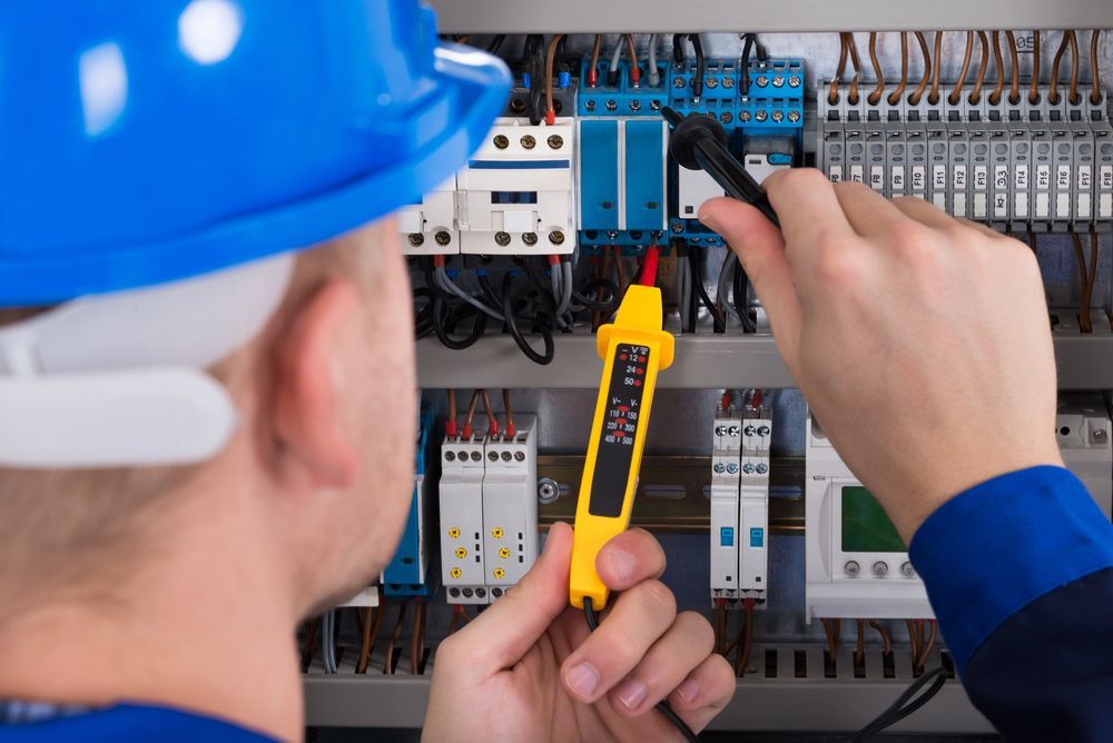 Técnico probando un panel eléctrico con un comprobador de voltaje y un multímetro.