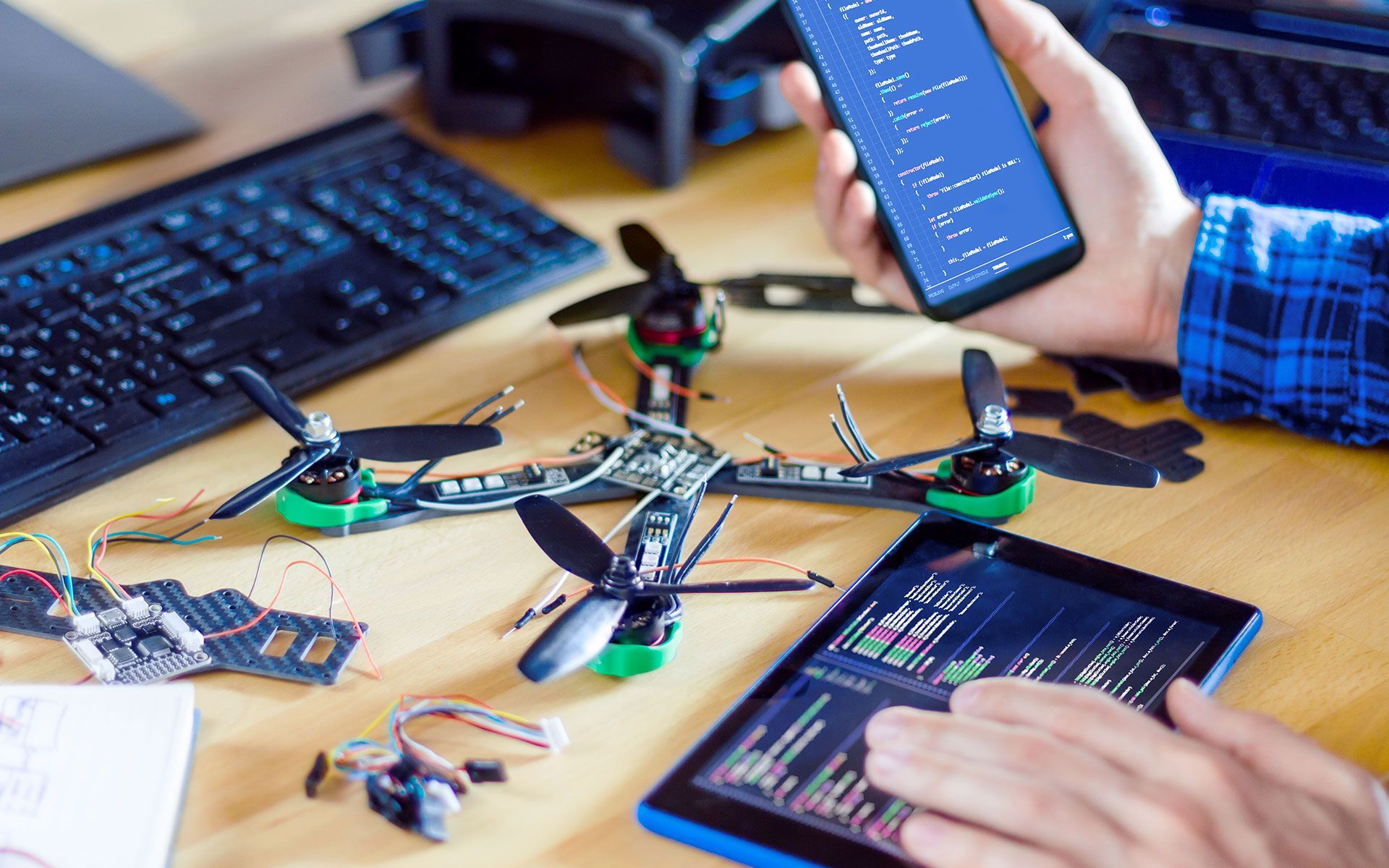 Person building a drone, using a smartphone and tablet to program it.