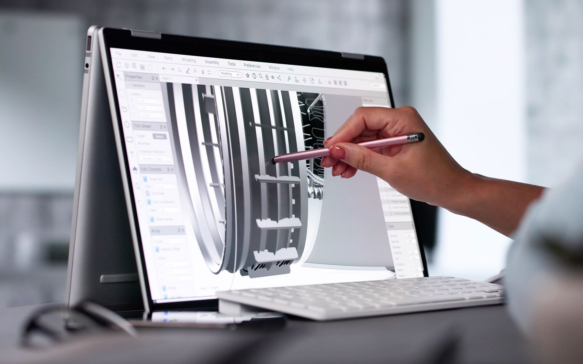Person using a stylus to design on a laptop with a complex 3D rendering.