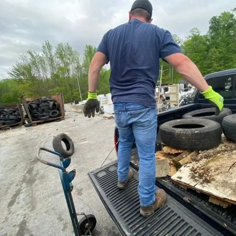 A man is loading tires into the back of a truck