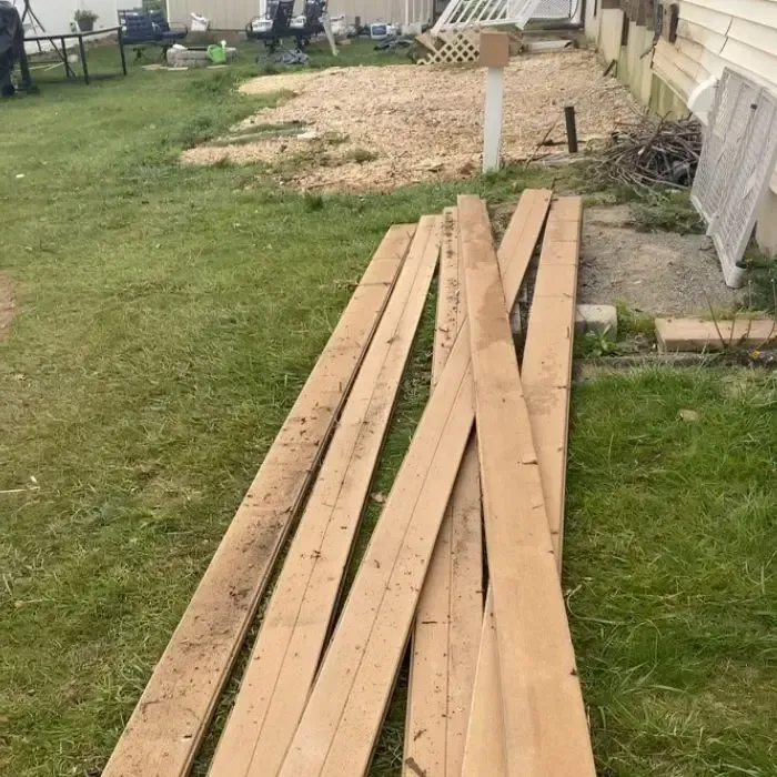 a pile of wood is sitting in the grass in front of a house .