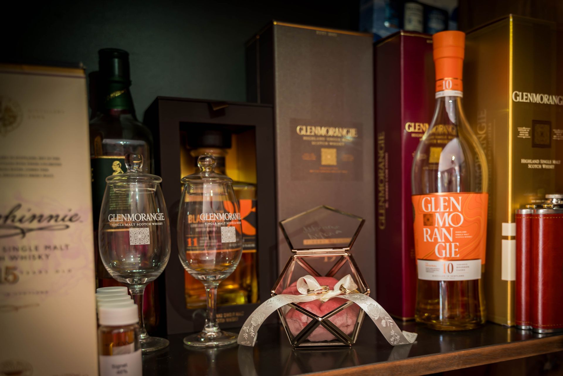 Een plank vol met flessen alcohol en glazen.