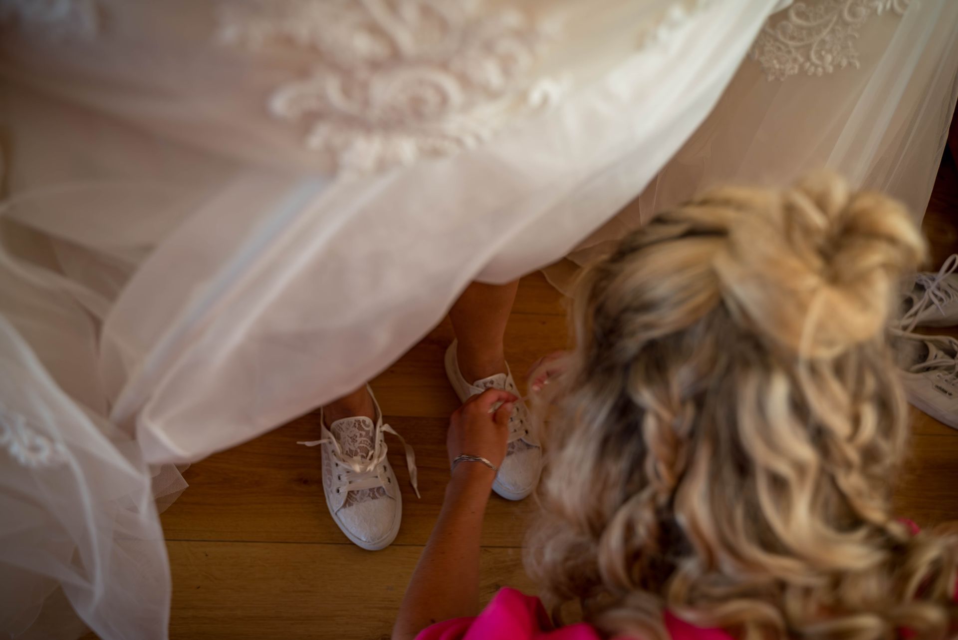 Een vrouw strikt de veters van de schoenen van haar bruid.