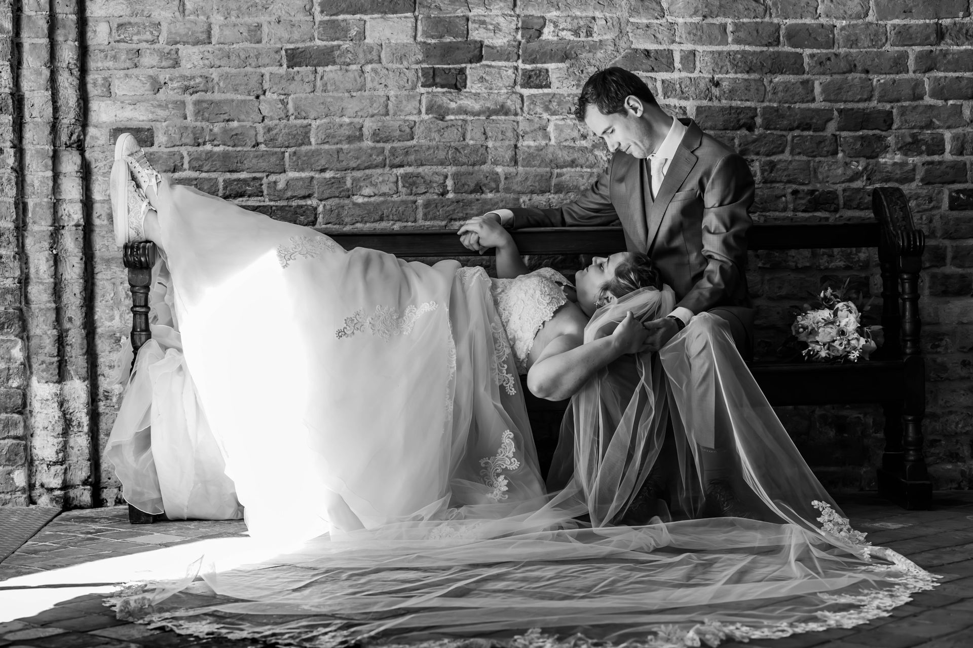 Een zwart-witfoto van een bruid en bruidegom die op een bankje zitten.