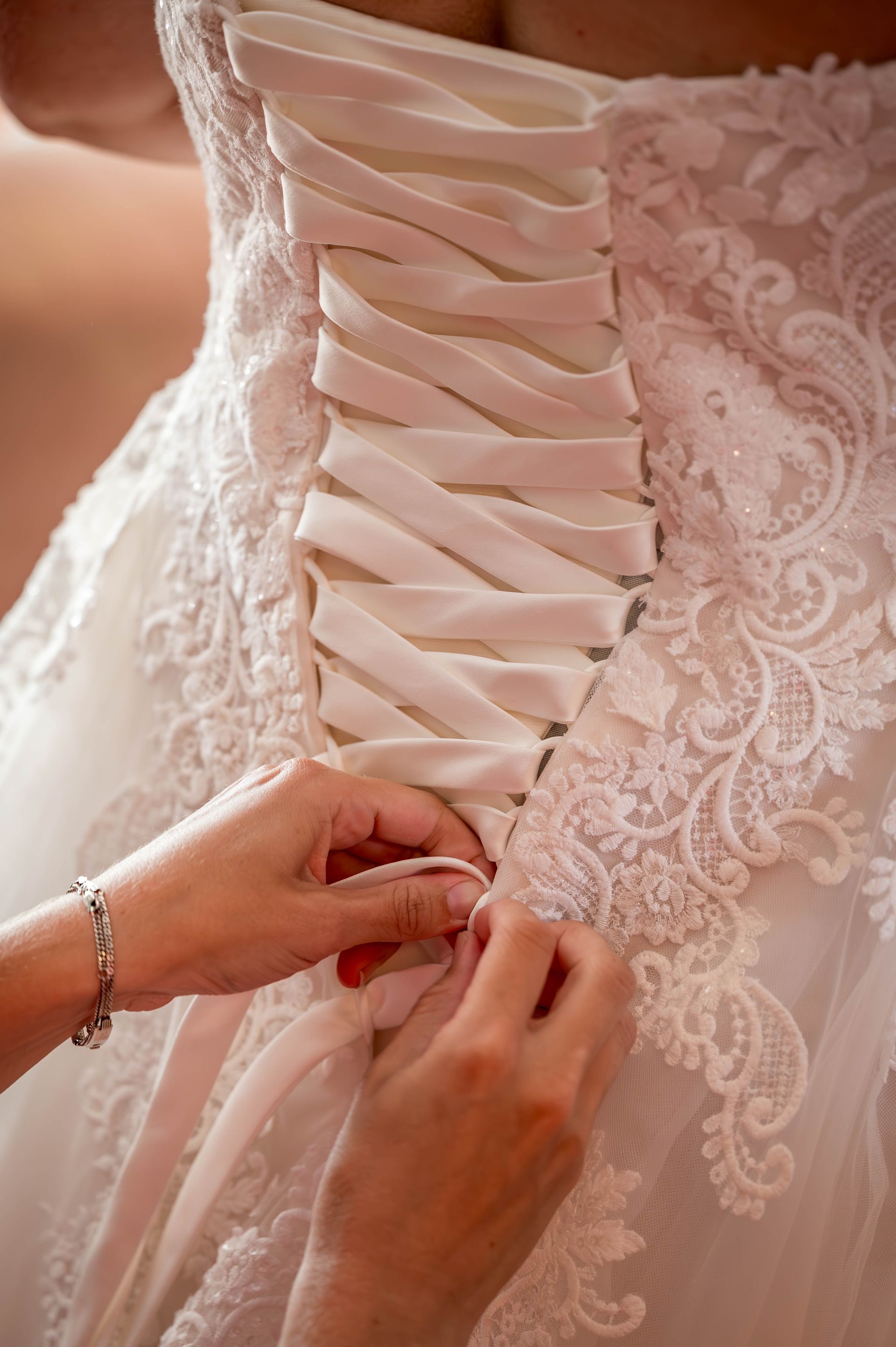 Een vrouw helpt een bruid met haar trouwjurk.