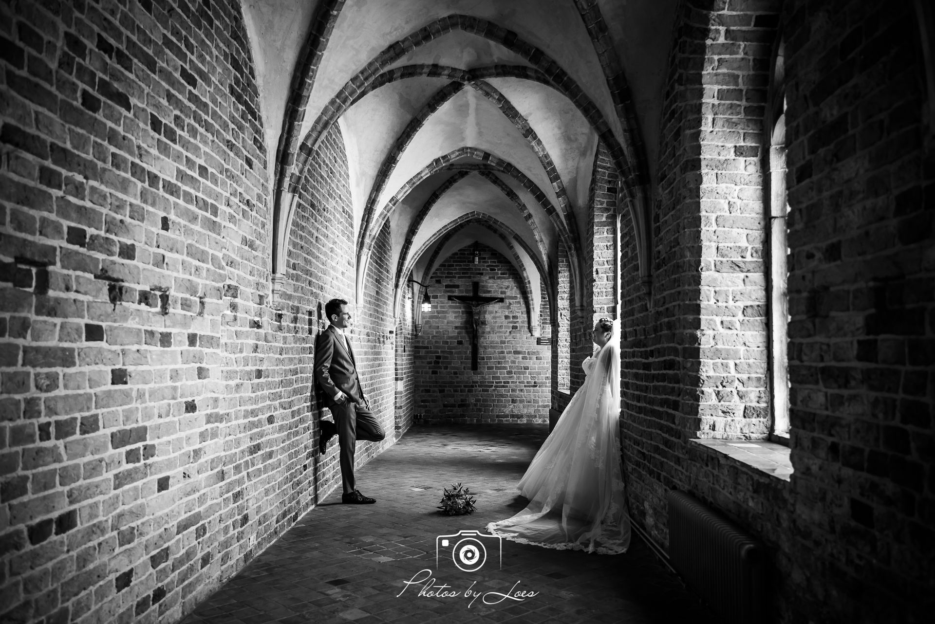 Een zwart-witfoto van een bruid en bruidegom die in een gang staan.