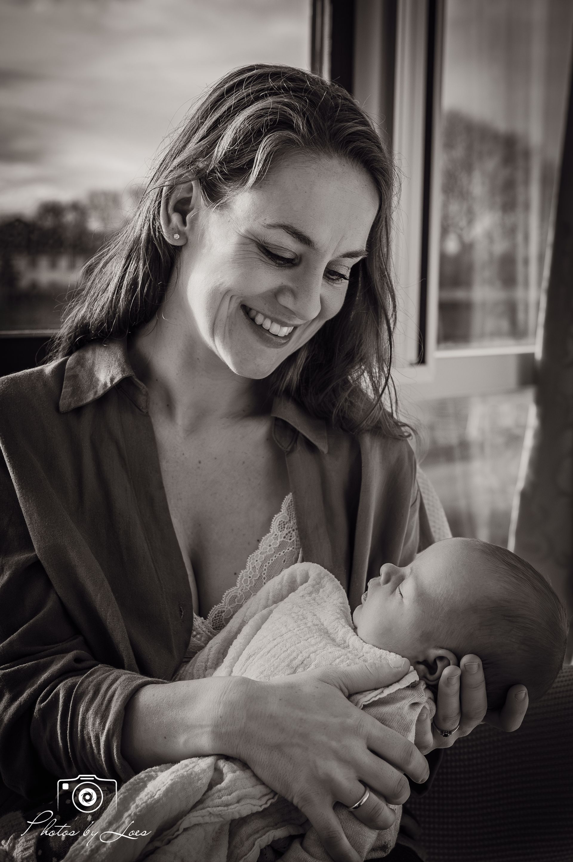 Op een zwart-witfoto houdt een vrouw een baby in haar armen.