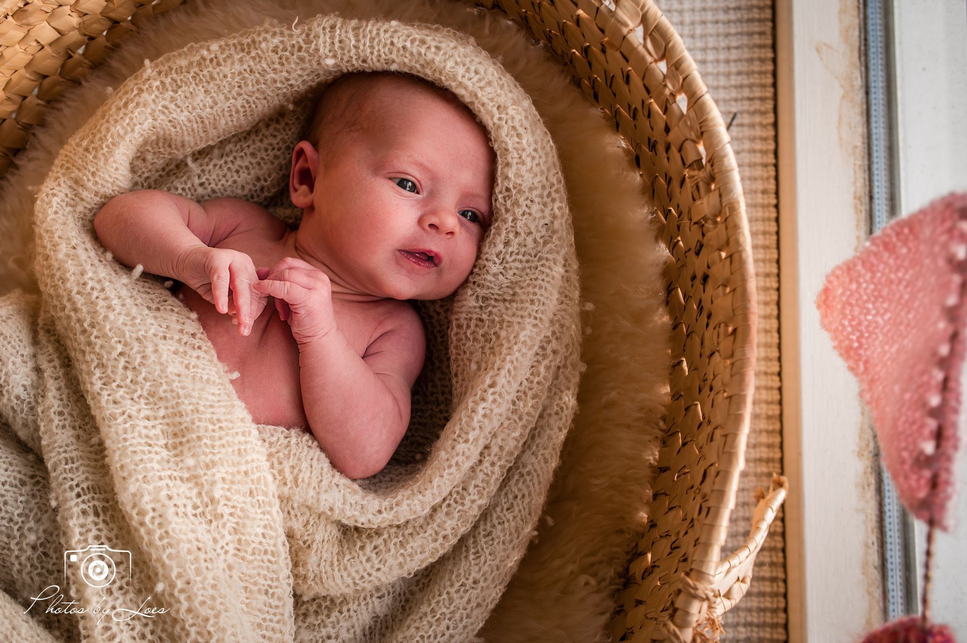 Een pasgeboren baby ligt in een mandje, gewikkeld in een deken.