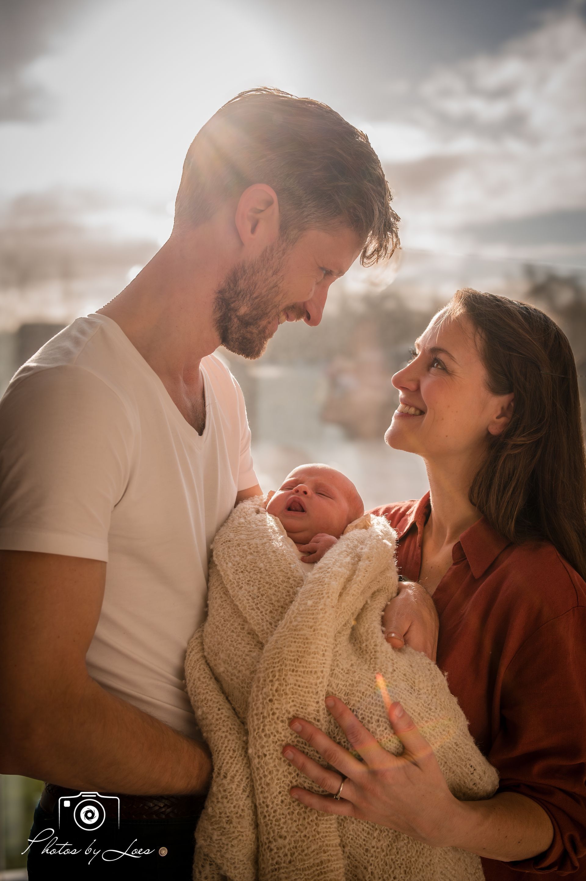 Een man en een vrouw houden een baby vast, gewikkeld in een deken.