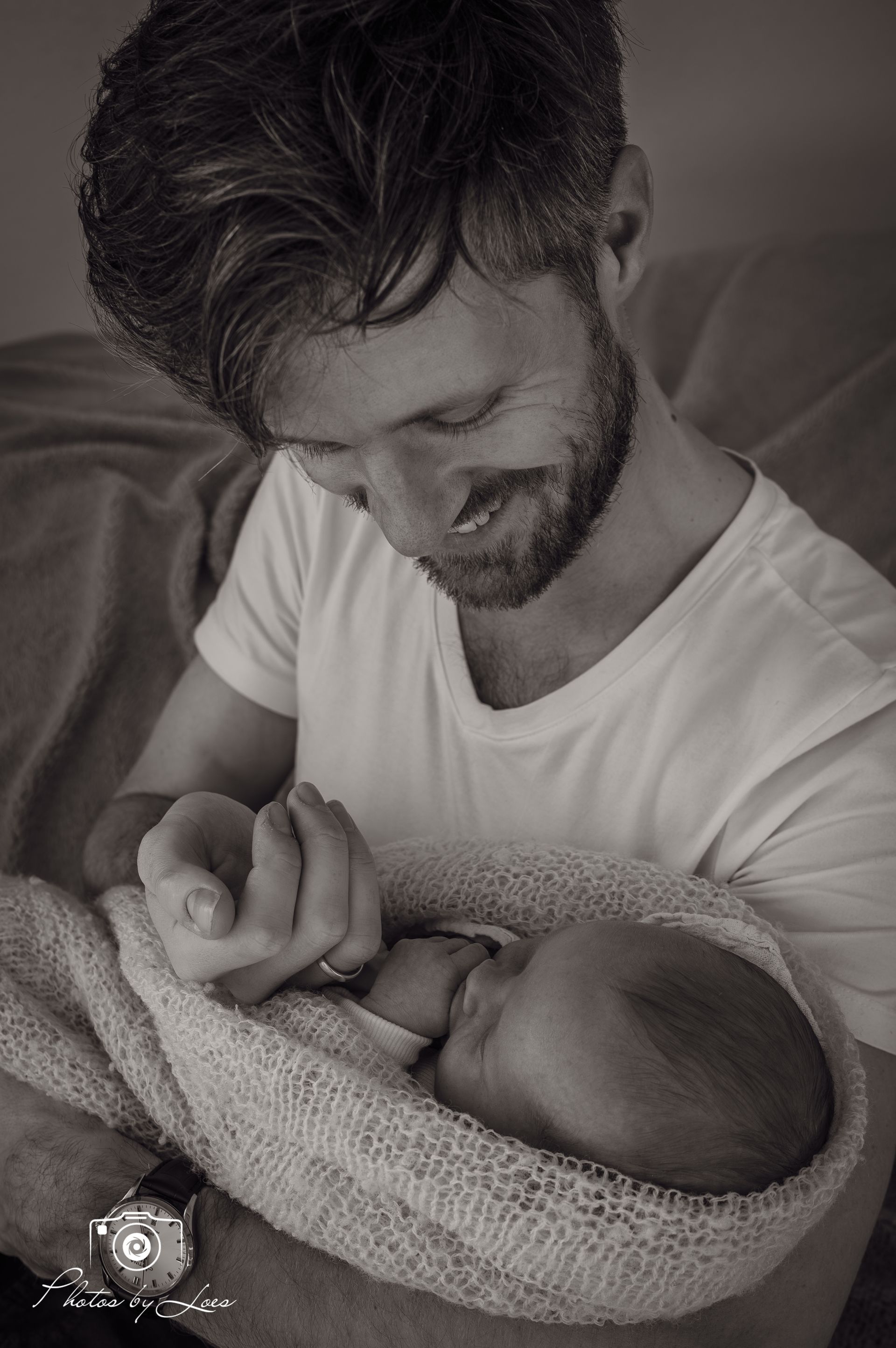 Een man houdt een pasgeboren baby vast, gewikkeld in een deken.