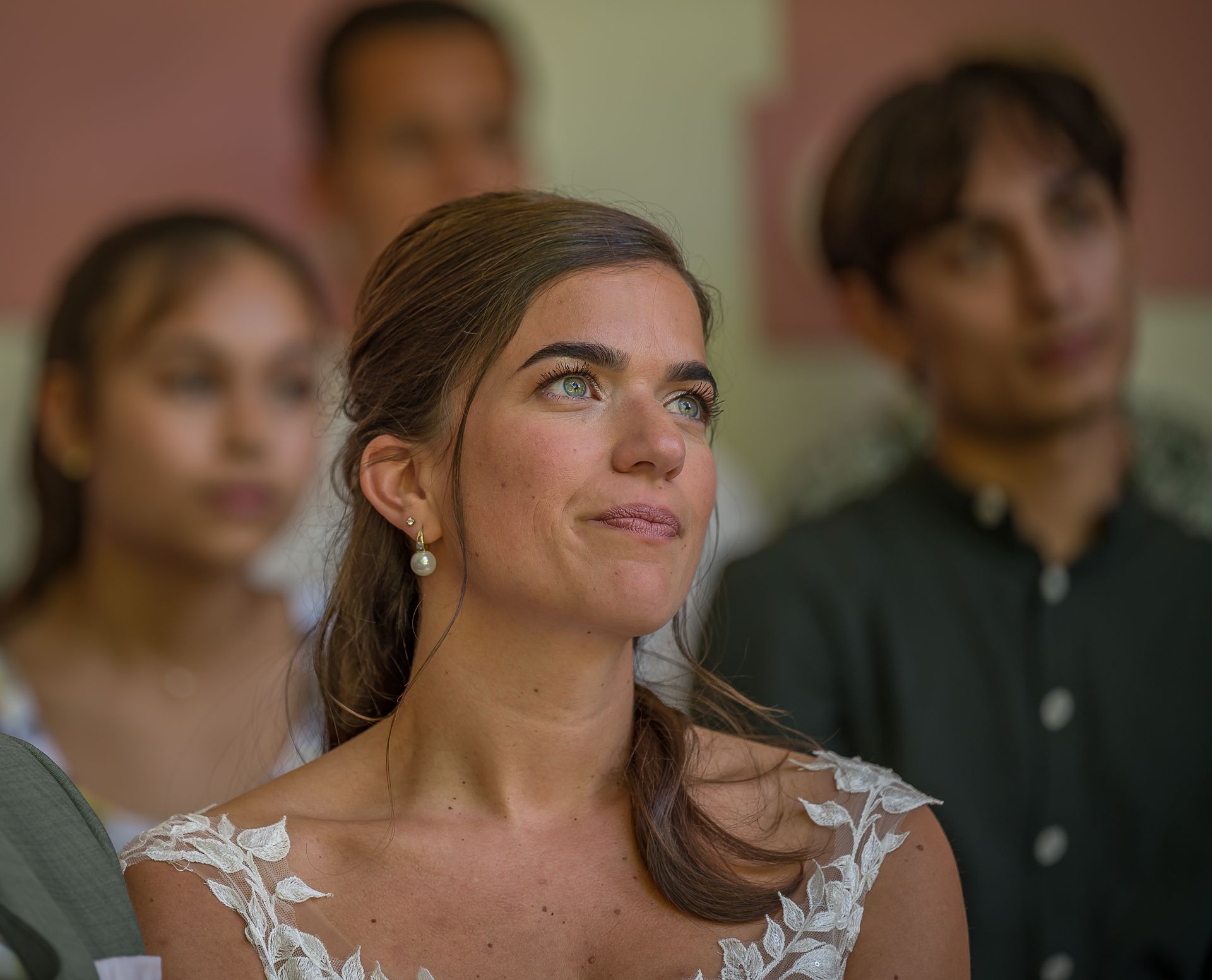 Een vrouw in een trouwjurk zit voor een groep mensen.