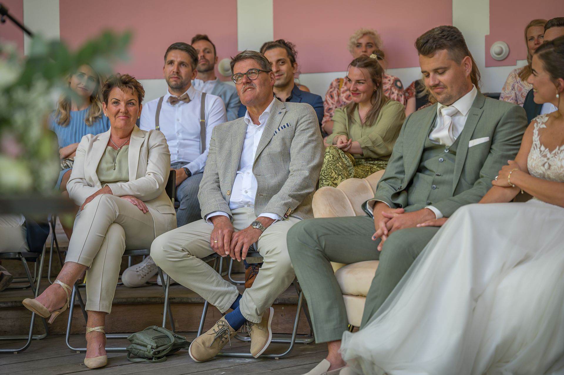 Een groep mensen zit op stoelen en kijkt naar een huwelijksceremonie.