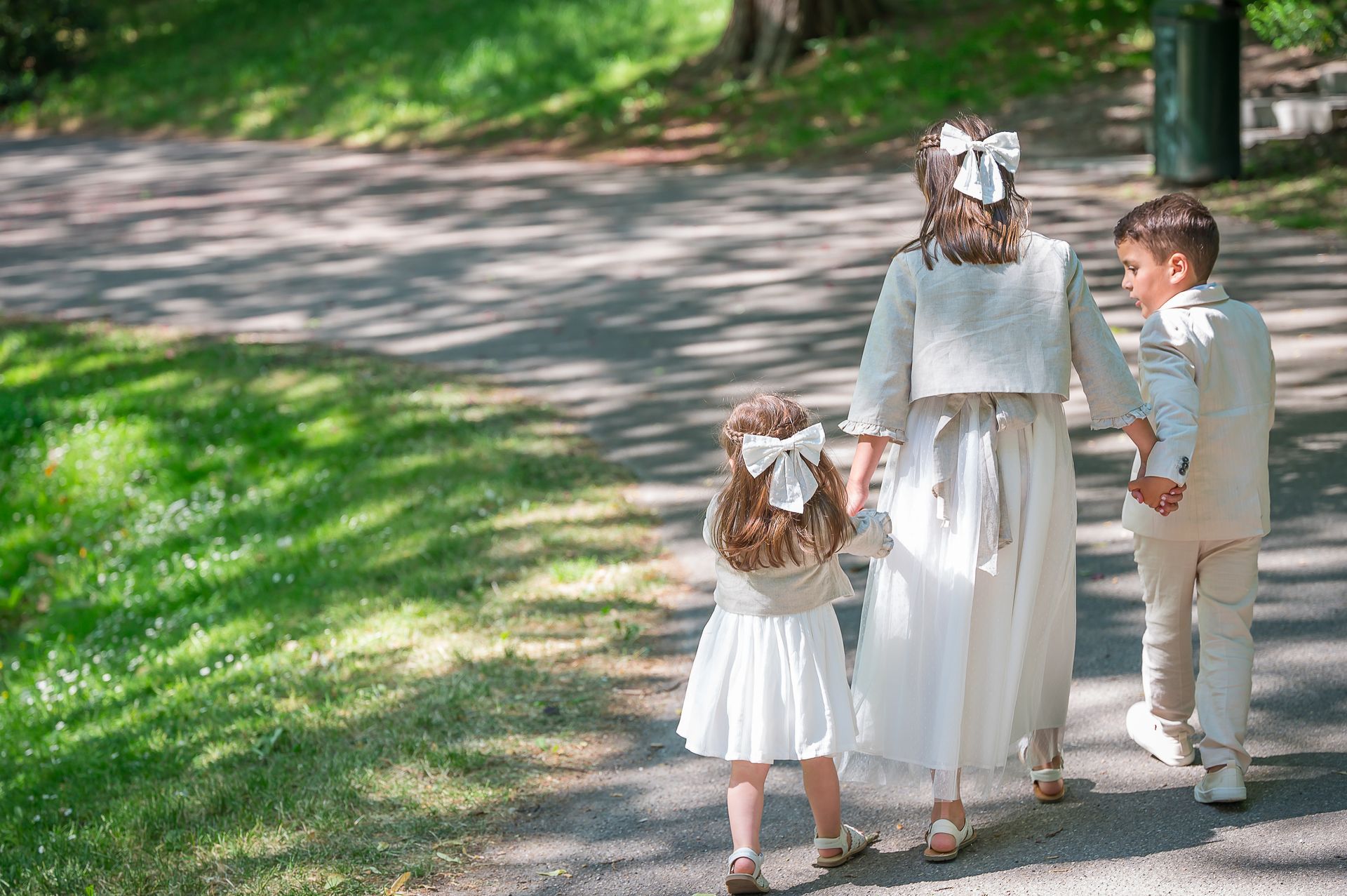 Een jongen en twee meisjes lopen hand in hand over een pad.